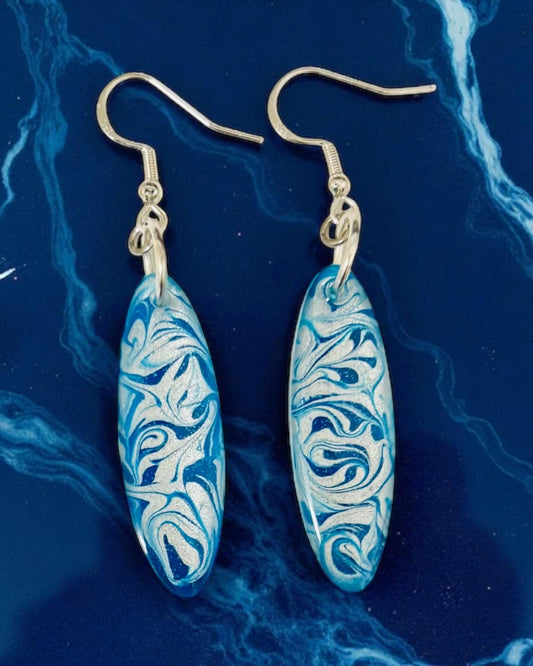 Blue and silver marbled earrings on a blue marbled background